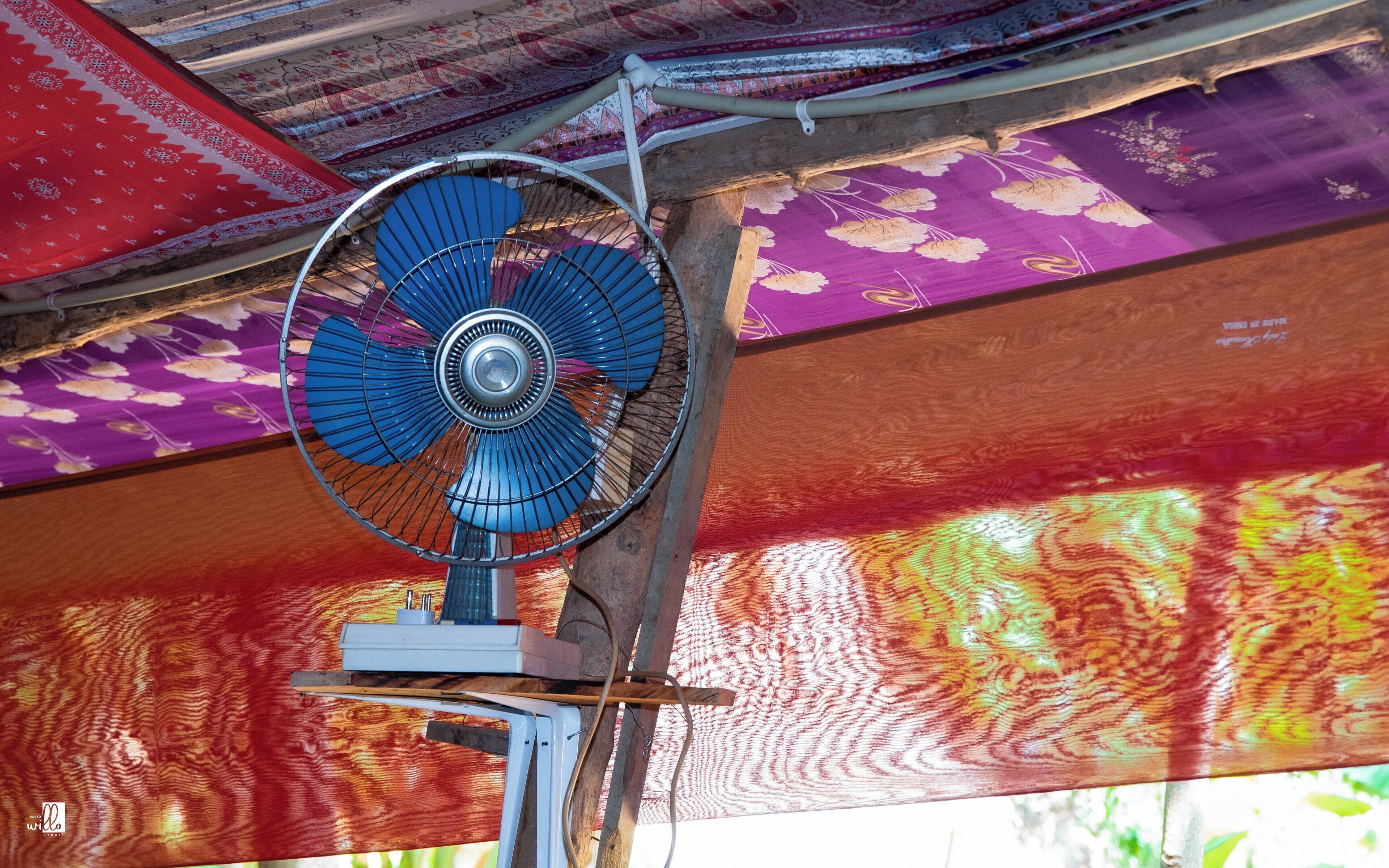 Un ventilateur de plafond aux motifs bleus et blancs, fixé sur une structure en bois.