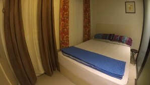 A bedroom with a bed, curtains, and a framed picture on the wall. - La Casa Parañaque (Paranaque)