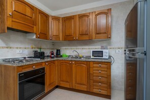 Una cocina con armarios de madera, microondas, estufa y refrigerador.