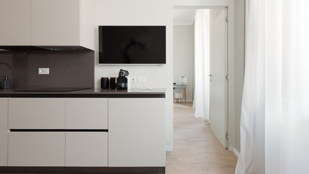 A modern kitchen with a flat-screen TV, a coffee machine, and a kettle.