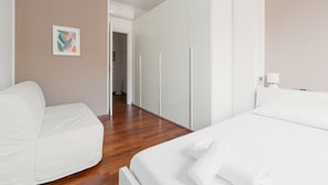 Une chambre d’hôtel comprenant un lit, un canapé, une armoire et un couloir menant à une autre pièce.