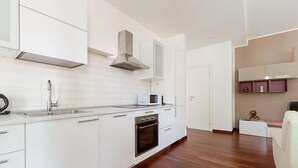 Une cuisine moderne avec des meubles blancs, une hotte en acier inoxydable, un four encastré et un four à micro-ondes.