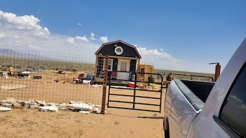 A fenced area with a building, a gate, and a vehicle.