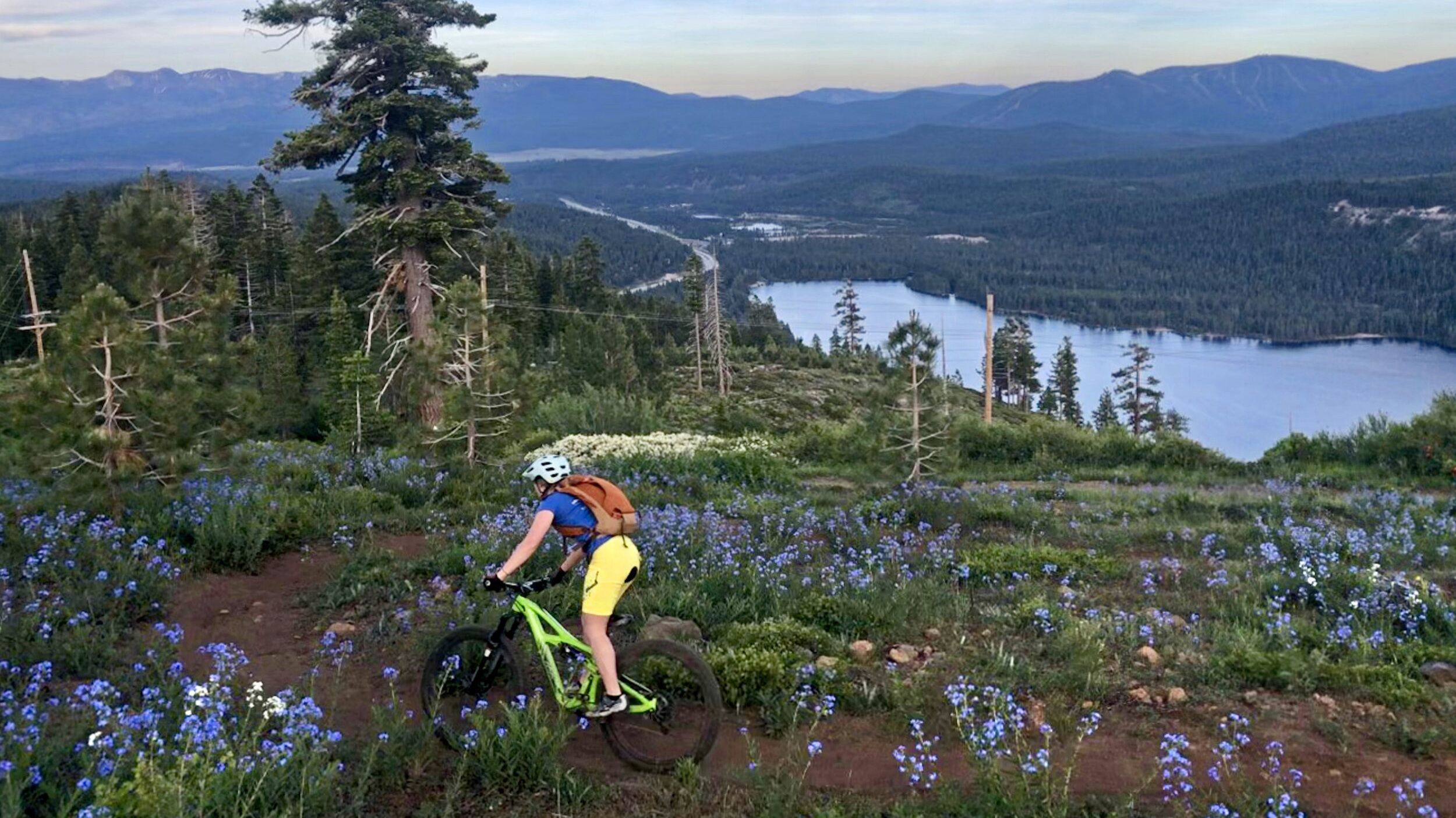 Ein Mountainbiker auf einem Pfad, im Hintergrund ein See und Berge.