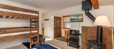 Una habitación con literas, microondas, estufa, una silla y un cuadro en la pared.