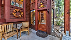 A wooden building with a 'Welcome' sign, a wreath on the wall, and two wooden benches outside. - Donner Lake Inn (Truckee)