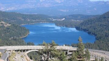 Uma ponte sobre um lago, rodeado por montanhas e florestas densas.