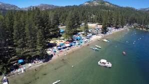 A coastal area with a beach, boats, and a forested hillside. - Donner Lake Inn (Truckee)