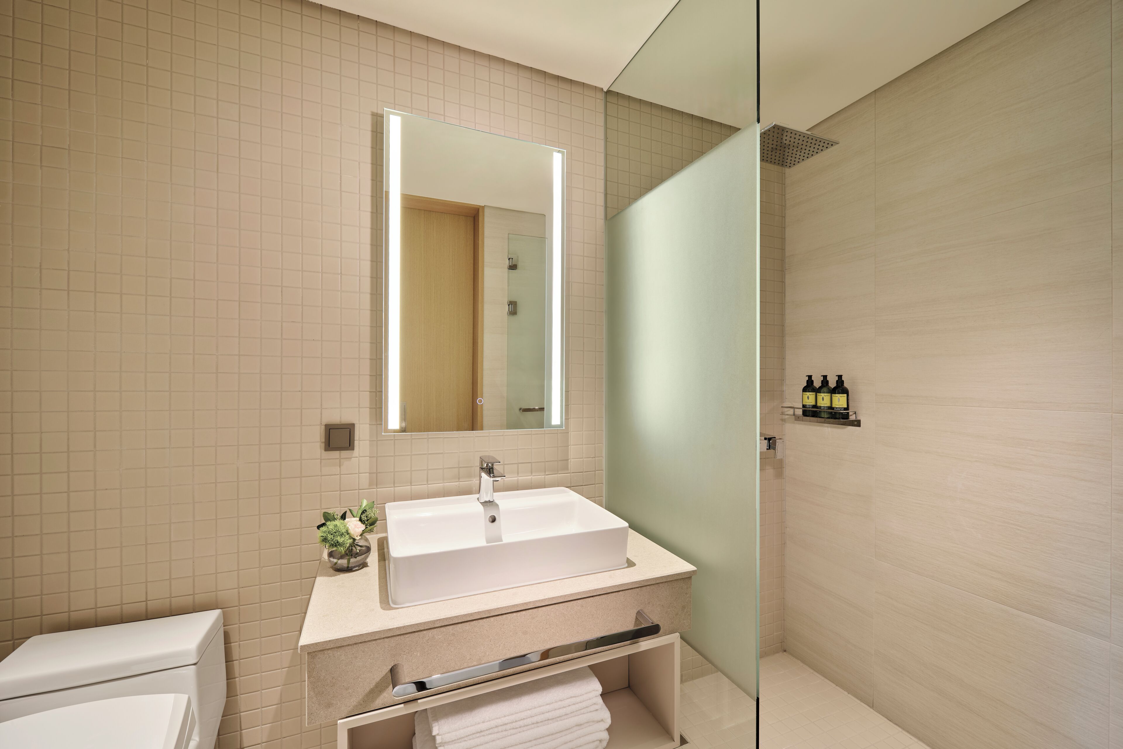 A modern bathroom with a large mirror, a sink, a toilet, and a shower area.