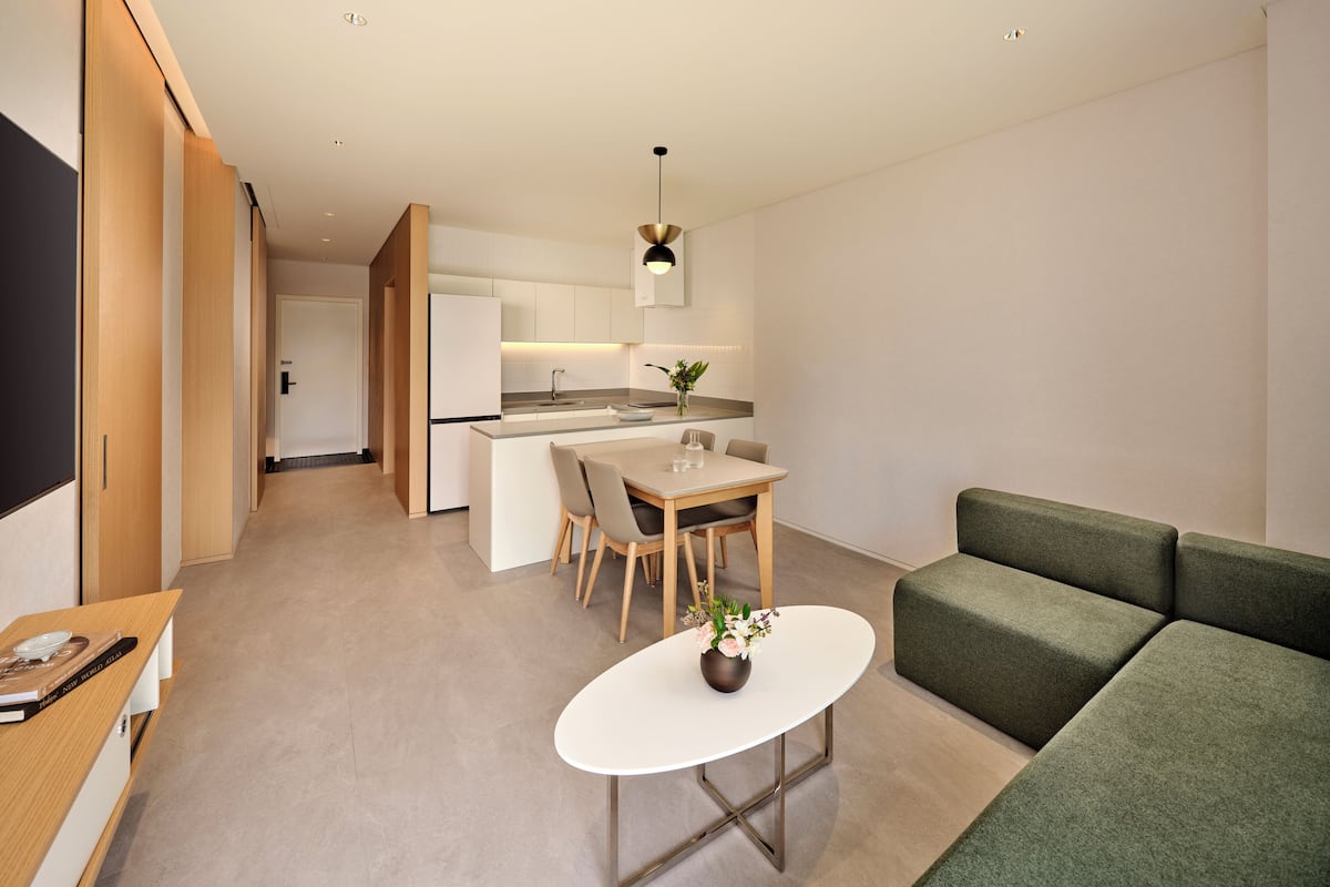 A modern interior with a dining area, kitchen, and a green sofa.