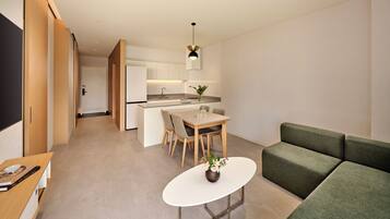 Un intérieur moderne comprenant un coin repas, une cuisine et un canapé vert.