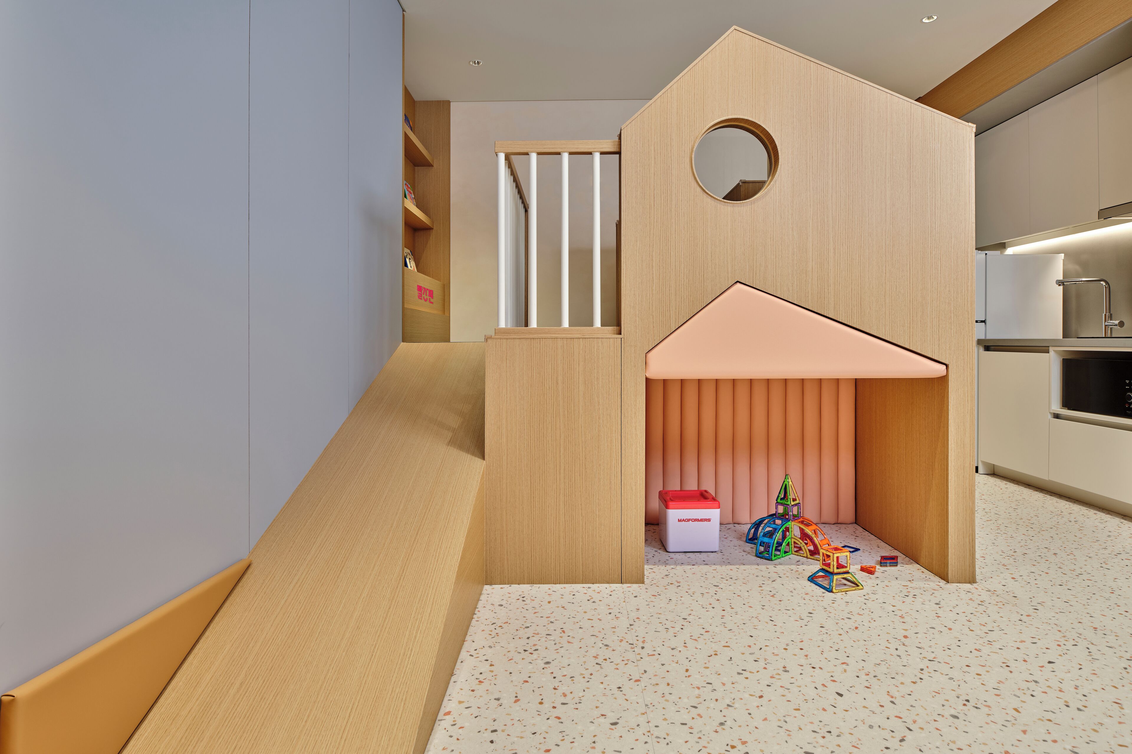 A children's play area with a slide, a small playhouse, and toys on the floor.