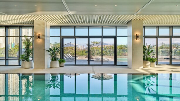Ein moderner, überdachter Pool mit Glaswänden, Blumentöpfen und Blick auf die Stadt.