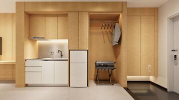 Een moderne keuken met een inbouwoven, een koelkast en een klein zithoekje met een bank.