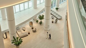 Eine großzügige Lobby mit hohen Decken, großen Fenstern und moderner Möblierung.