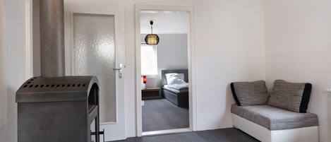A compact room with a built-in wood stove, a glass table, and a sofa.