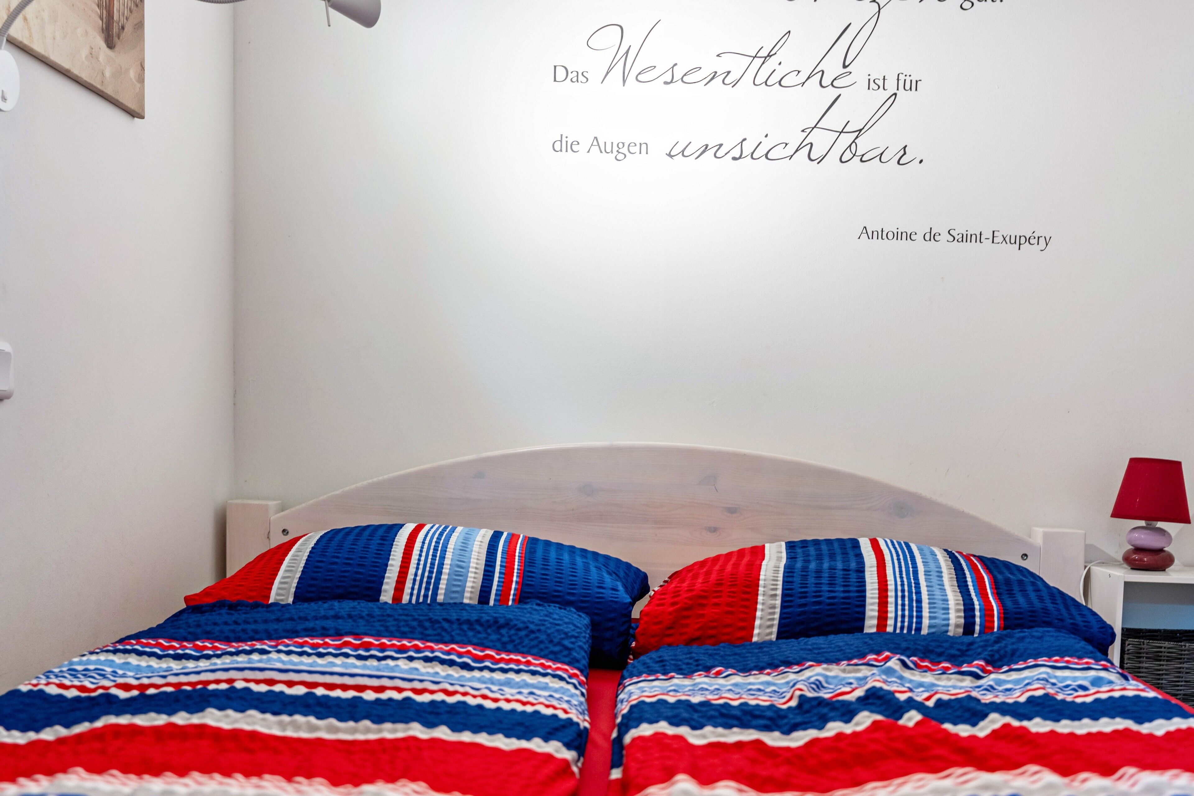 Een slaapkamer met een bed, een muisbrief en een rode lamp op een nachtkastje.