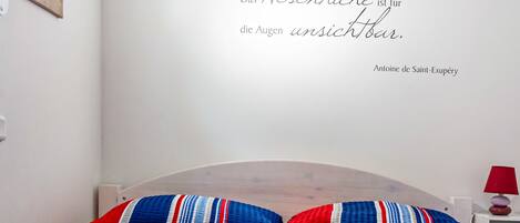 Een slaapkamer met een bed, een muisbrief en een rode lamp op een nachtkastje.