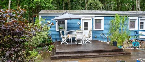 Une maison bleue avec une terrasse en bois, du mobilier d’extérieur et un jardin.