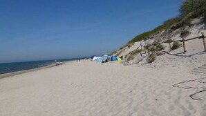 Une plage avec des tentes et une clôture le long du rivage.