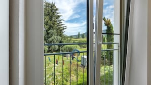 A room with a large window overlooking a grassy area with trees and a clear sky.