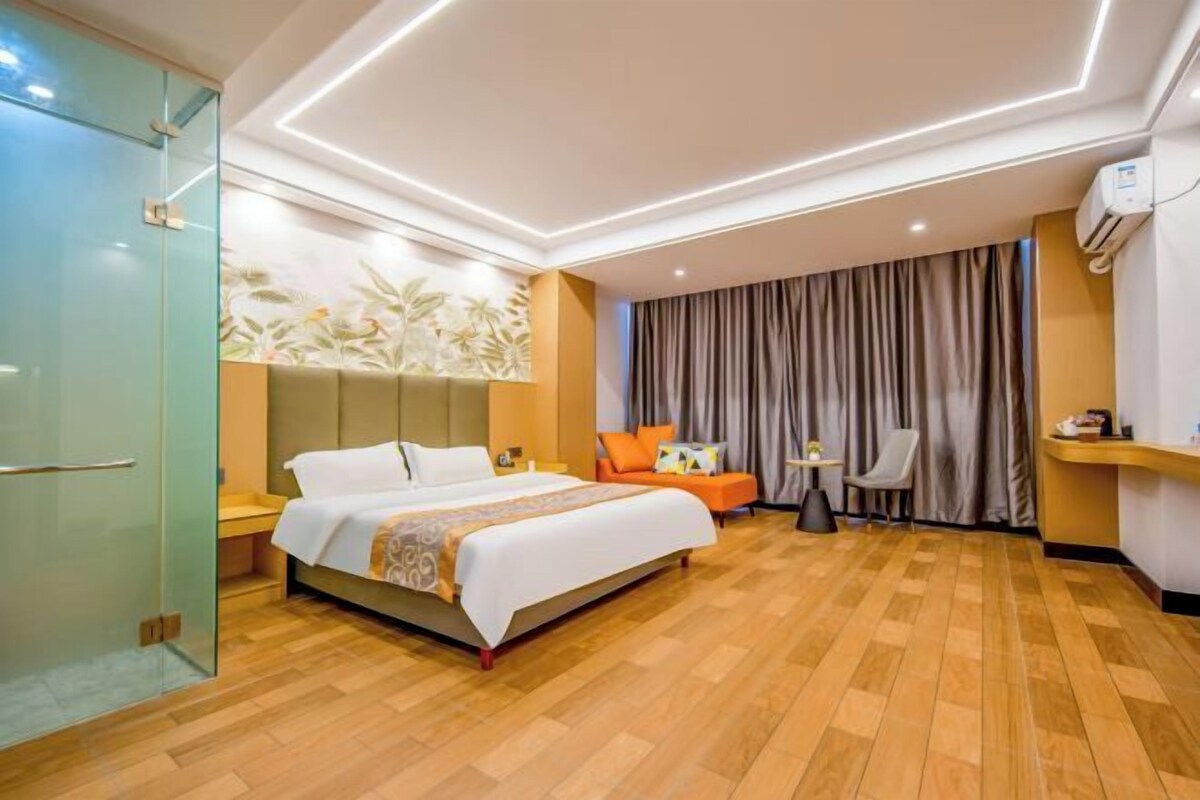 A hotel room with a bed, a desk, a chair, a glass door, and a curtain.