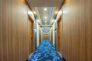 A hotel hallway with wooden walls, a blue carpet, and a sign indicating a room number. - New World Holiday Hotel (Lingshui City) (Lingshui)