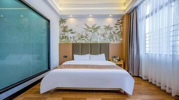 Une chambre d’hôtel avec un grand lit, un mur en verre et une vue sur les palmiers.
