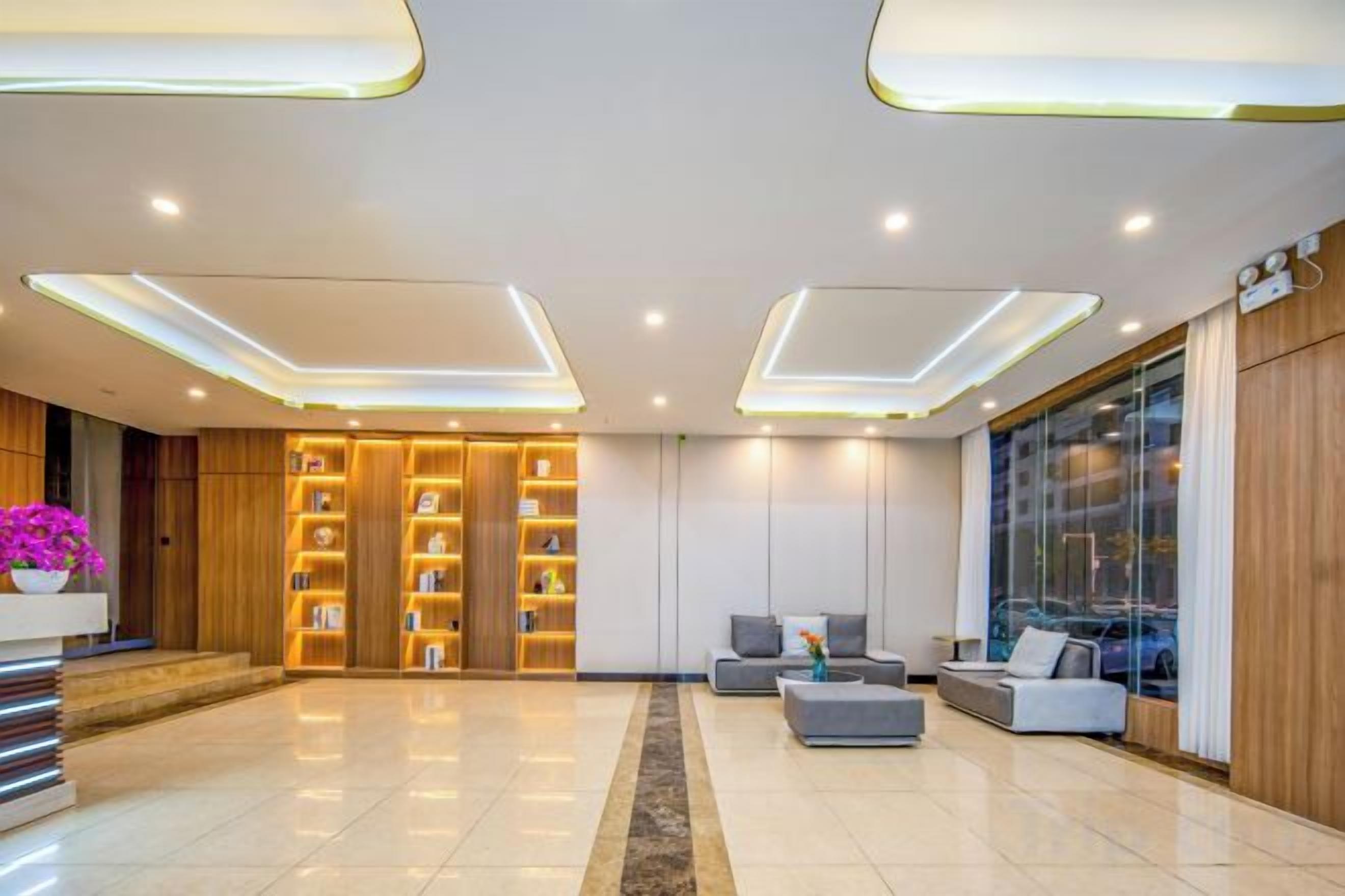 A modern lobby with a reception desk, seating area, and a large window.