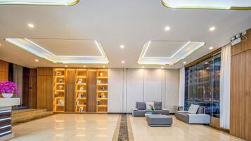 A modern lobby with a reception desk, seating area, and a large window.
