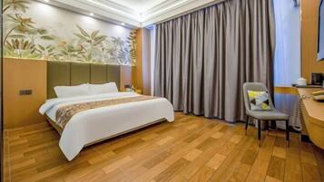Een hotelkamer met een bed, bureau, stoel en gordijn.