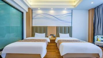 Een hotelkamer met twee bedden, een groot raam, een moderne wanddecoratie en een nachtkastje met een lamp.
