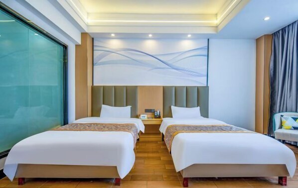 A hotel room with two beds, a large window, a modern wall art piece, and a nightstand with a lamp. - New World Holiday Hotel (Lingshui City) (Lingshui)