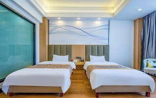Habitación de hotel con dos camas, un ventanal grande, una obra de arte moderna en la pared y una mesita de noche con lámpara.