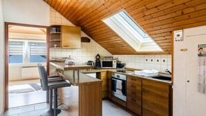 A kitchen with wooden cabinets, a microwave, a kettle, and a window with a skylight. - Apartment 'Fewo Georg' with Wi-Fi (Pfullendorf)