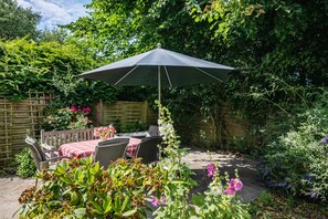 An outdoor patio with a table and chairs, a wooden fence, and various plants.