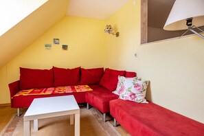 A room with a red sectional sofa, a white coffee table, and a lamp.