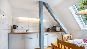 Eine Küche mit weißen Schränken, einer Holz Arbeitsplatte, einer Kaffeemaschine, einer Mikrowelle und einem Geschirrspüler.