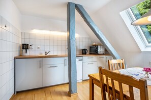 A kitchen with white cabinets, a wooden countertop, a coffee maker, a microwave, and a dishwasher.