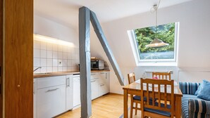 Eine moderne Küche mit weißen Schränken, einem Holztisch und einem Fenster mit Blick auf Grünflächen.