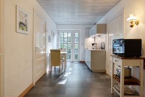 A hallway with a dining area, kitchen, and a television on a table.