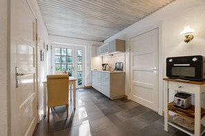 A modern kitchen with white cabinets, a wooden chair, and a built-in microwave.