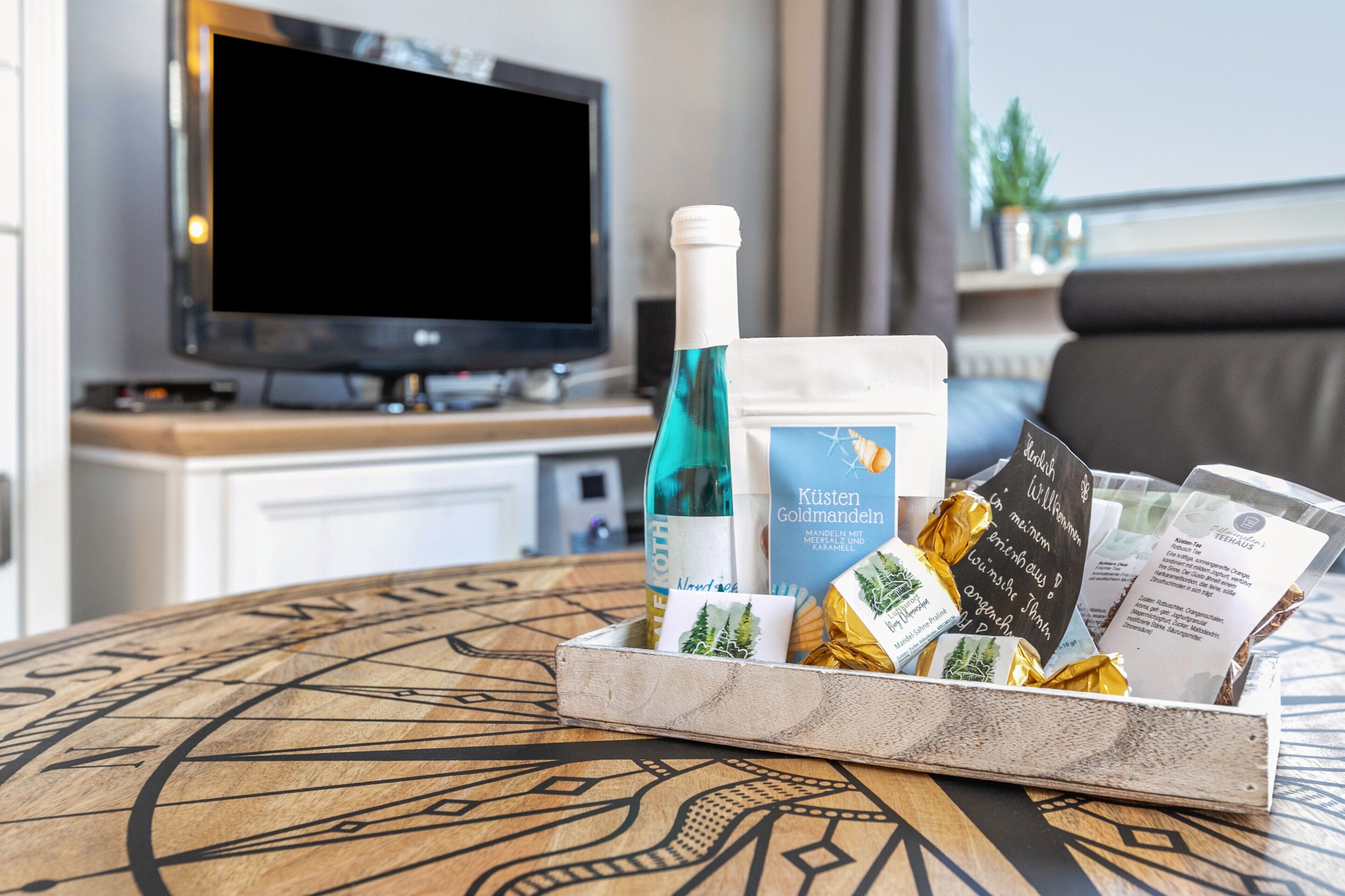 A tray with a bottle, a card, and some wrapped items on a table with a compass design.