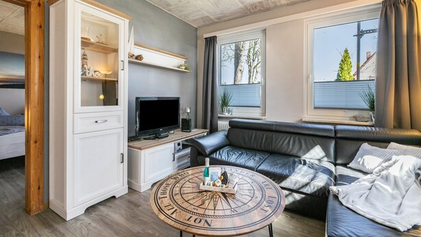 Ein Wohnzimmer mit einer Couch, einem Fernseher, einem Schrank und einem runden Couchtisch.