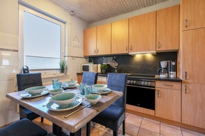 A kitchen with wooden cabinets, a dining table set with bowls and plates, a microwave, and a coffee maker.