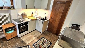 Une cuisine compacte dotée d’un four encastré, d’un évier et d’une porte en bois.