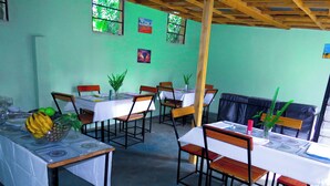 Un espace repas avec des tables dressées pour les repas, des chaises et une plante sur chaque table.