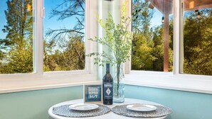 A table with two plates, a bottle of wine, and a framed sign in a room with large windows.