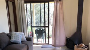 Una sala de estar con un sofá, una cesta de mimbre y un estufa de leña.