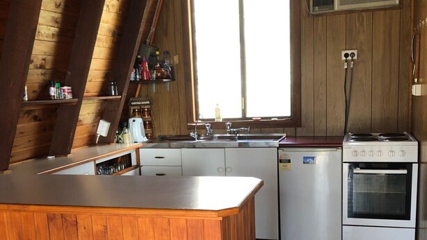Una cocina con isla de madera, pileta, estufa y refrigerador.